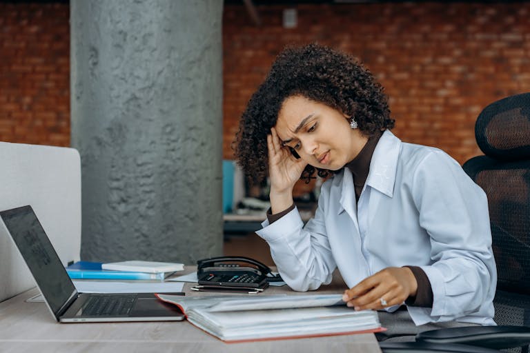 Businesswoman experiencing fatigue while working on financial paperwork at her desk.