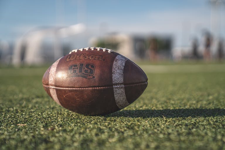 Close-up of a Wilson football on green grass in an outdoor sports setting, perfect for sports-themed visuals.